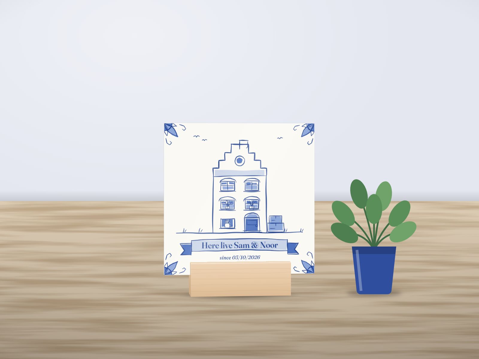 A house tile on its wooden stand: a canal house in Delft blue, “Here live Sam & Noor”. A mockup, not a photo.